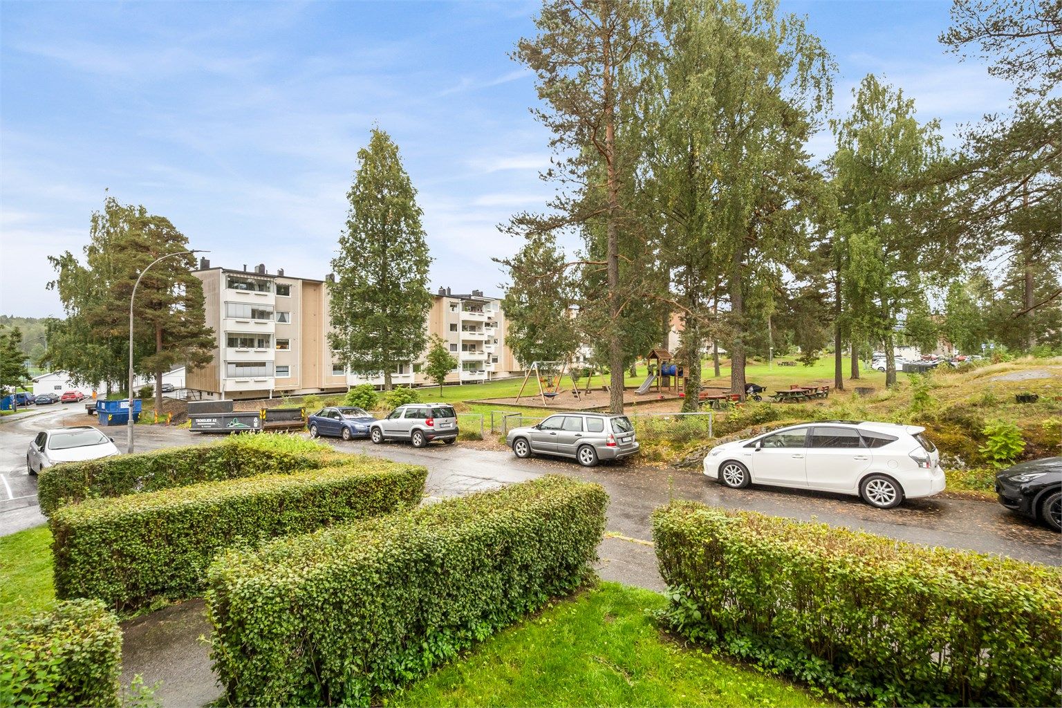 Utsyn fra balkongen mot grønne fellesarealer og lekeplass.