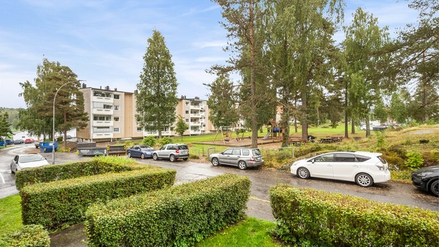 Utsyn fra balkongen mot grønne fellesarealer og lekeplass.