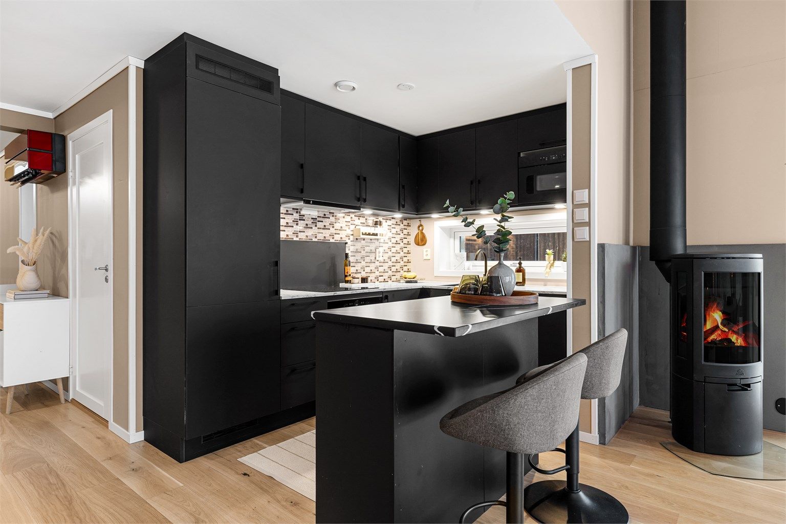 Laminerte benkeplater. Oppvaskkum med ett-greps armatur. Malt flate mellom benkeplate og overskap. Overbelysning og stikkontakter over benk. Integrerte hvitevarer.