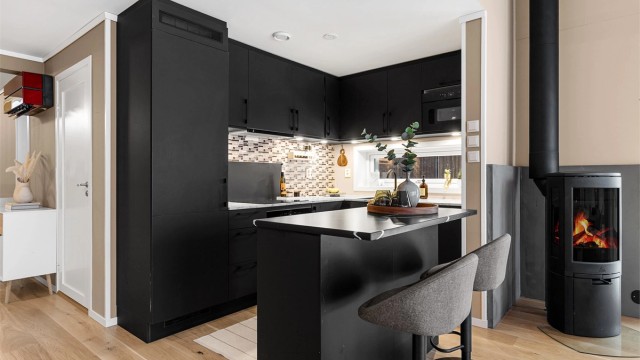 Laminerte benkeplater. Oppvaskkum med ett-greps armatur. Malt flate mellom benkeplate og overskap. Overbelysning og stikkontakter over benk. Integrerte hvitevarer.