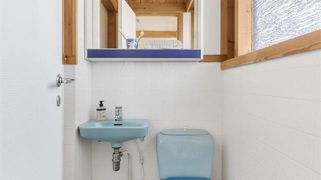Separat toalettrom med flislagt gulv med varme og vegghengt servant.