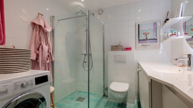 Badet er innredet med vegghengt toalett tilkoblet sisternekasse og egen dusjsone med glassfelt og glassdør. Dusjen er tilkoblet både hånd- og regndusj.