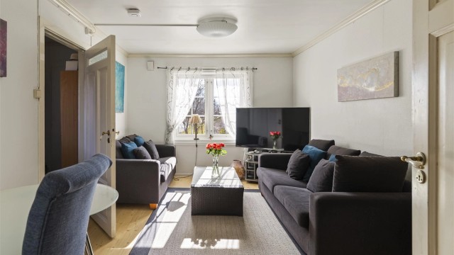 Stuen i utleiedelen har laminat på gulvet og plass til en sofagruppe.