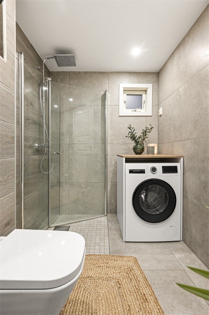 Videre er det dusjhjørne med glassdører i tillegg til opplegg for vaskemaskin.