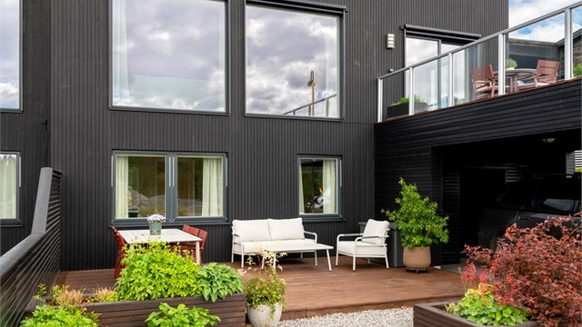 Boligen har en moderne fasade med stående bordkledning.