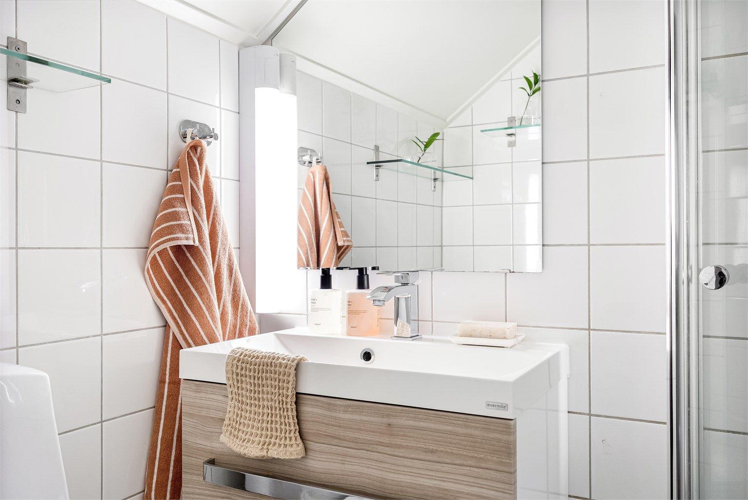 Badet er innredet med vegghengt servantinnredning med ovenpåliggende vask og det er speil, samt lys med stikkontakt over vasken.