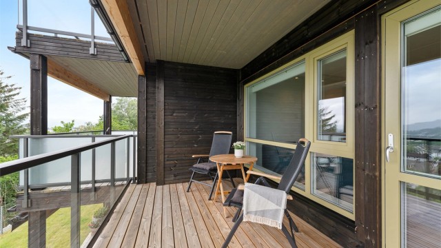 Lun og skjermet overbygd veranda med glassrekkverk