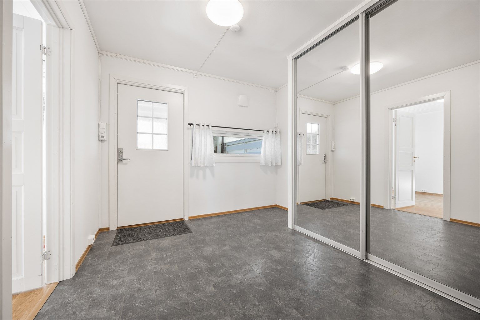 Romslig entré med en stor skyvedørsgarderobe for effektiv oppbevaring av yttertøy og sko.