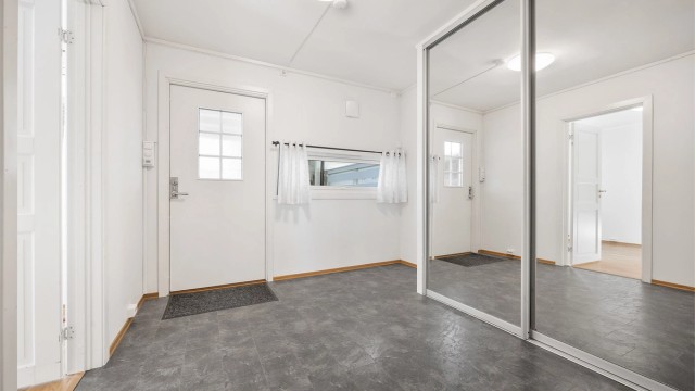 Romslig entré med en stor skyvedørsgarderobe for effektiv oppbevaring av yttertøy og sko.