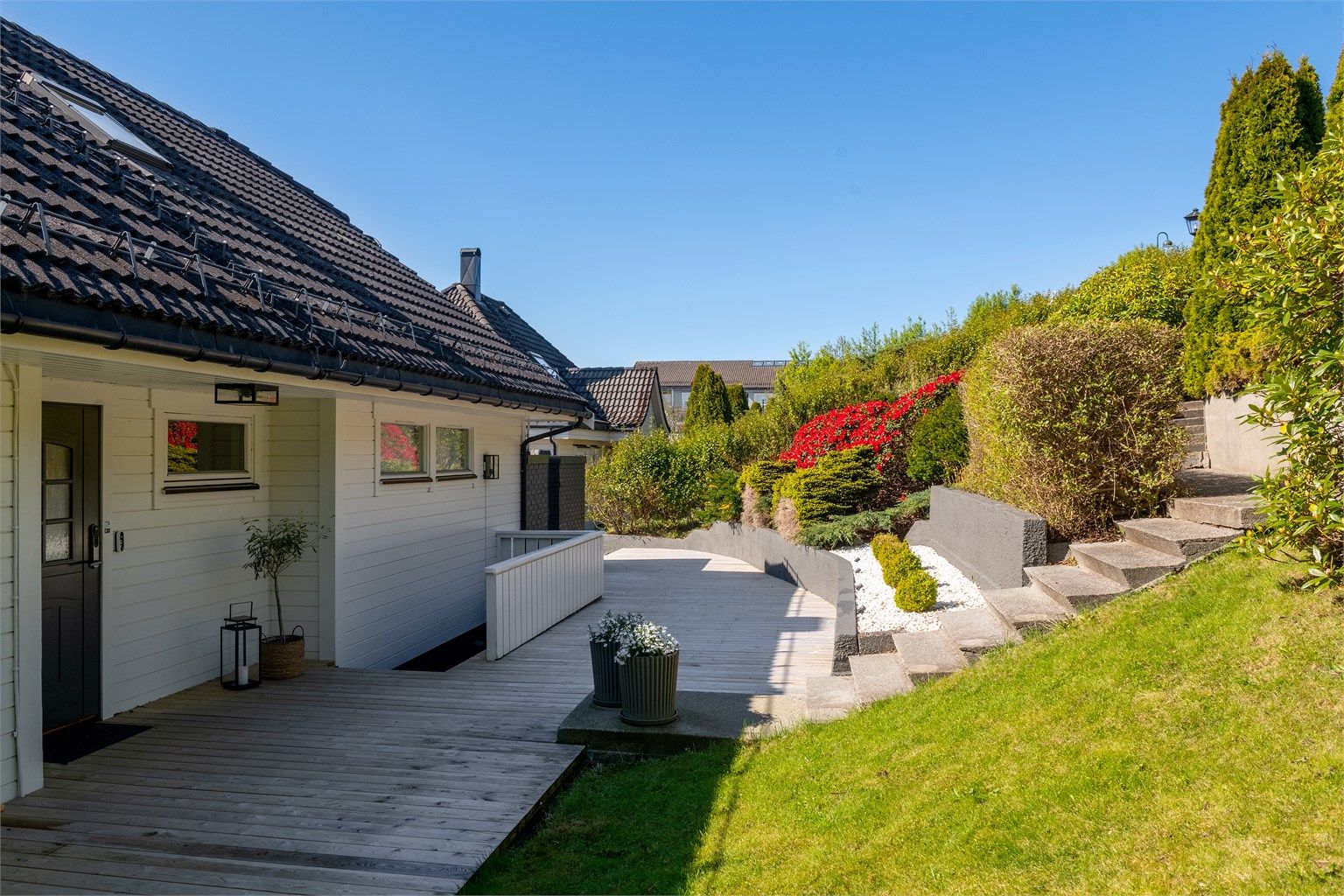 Tomten er pent opparbeidet med treterrasser og støpte trapper i terrenget.