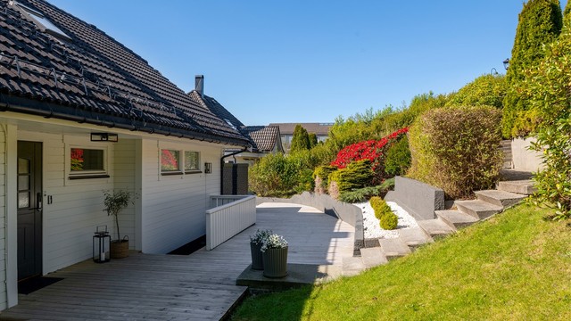 Tomten er pent opparbeidet med treterrasser og støpte trapper i terrenget.