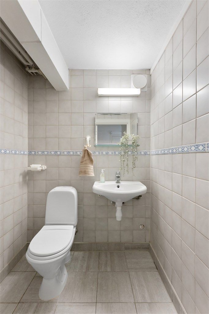 Toalettrom i kjelleren med flislagte overflater.