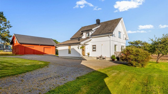 Gruset gårdsplass med god plass for biloppstilling foran garasjen og våningshuset.