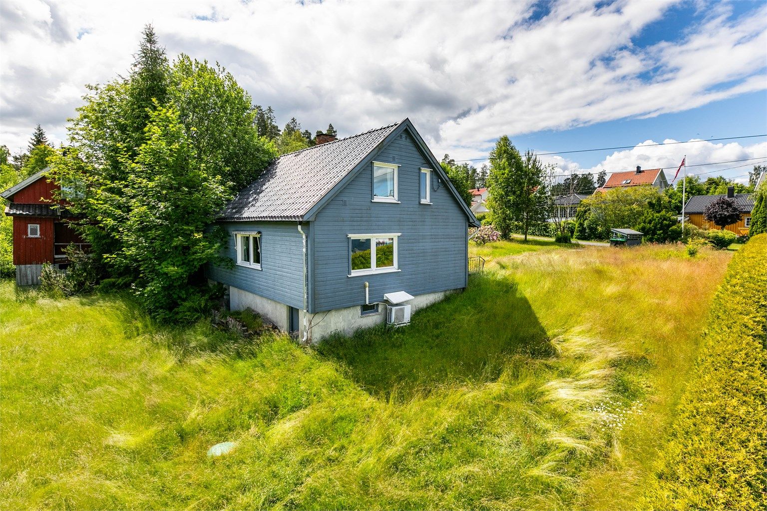 Tomten rundt huset er opparbeidet med plen, hekk og gruset gårdsplass. 