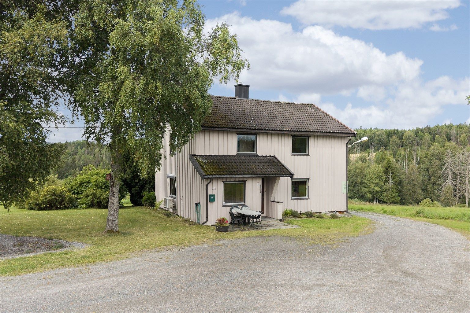 Våningshuset sett fra innkjørselen, med landlige omgivelser.