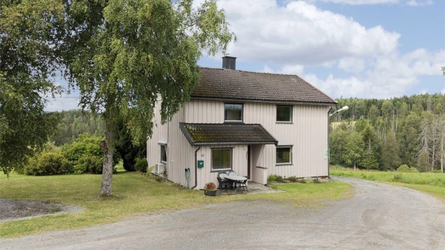 Våningshuset sett fra innkjørselen, med landlige omgivelser.