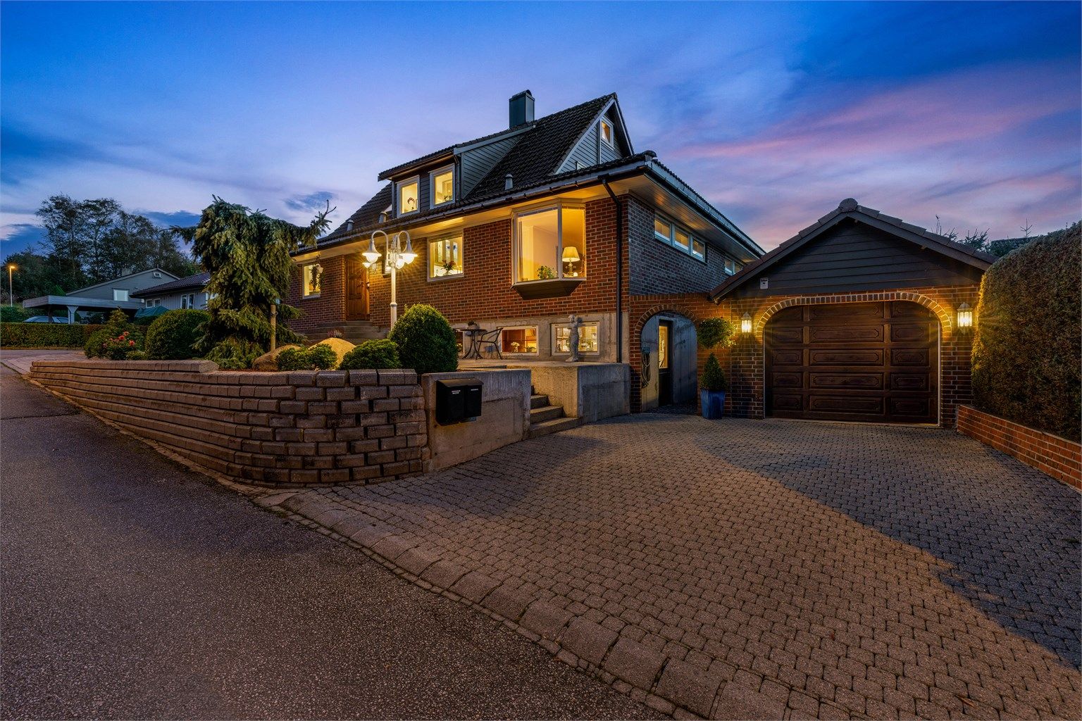 Stort gårdsrom på begge sider av huset med belegningsstein og garasje.