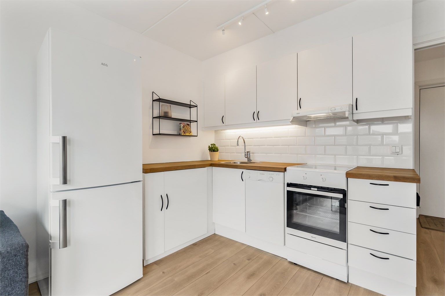 Pen kjøkkeninnredning med over- og underskap i hvit samt glatt utførelse