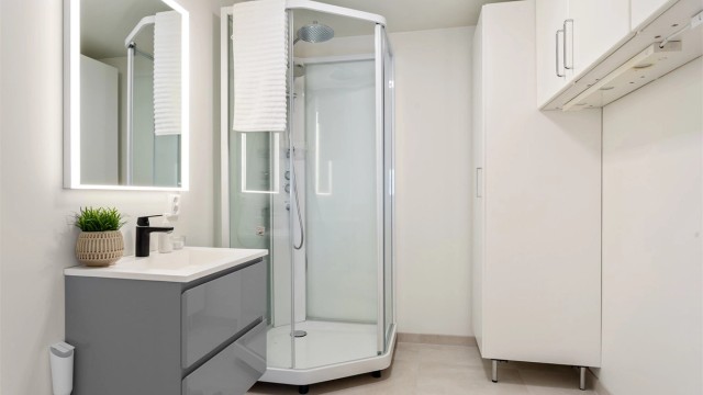 Bad/vaskerom med flislagt gulv med varme fra 2025/26. Malte vegg- og himlingsflater. Nytt speil og ny baderomsinnredning. (ubrukt) Dusjkabinett, høyskap og vegghengte skap er forholdsvis nytt og lite brukt.