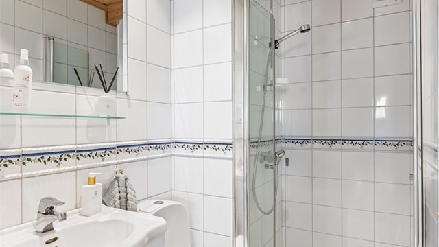 Det andre badet i underetasjen har flislagt gulv med gulvvarme og dusjhjørne.