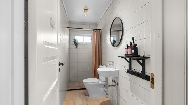 Badet i første etasje har flislagt gulv med gulvvarme og dusjhjørne.