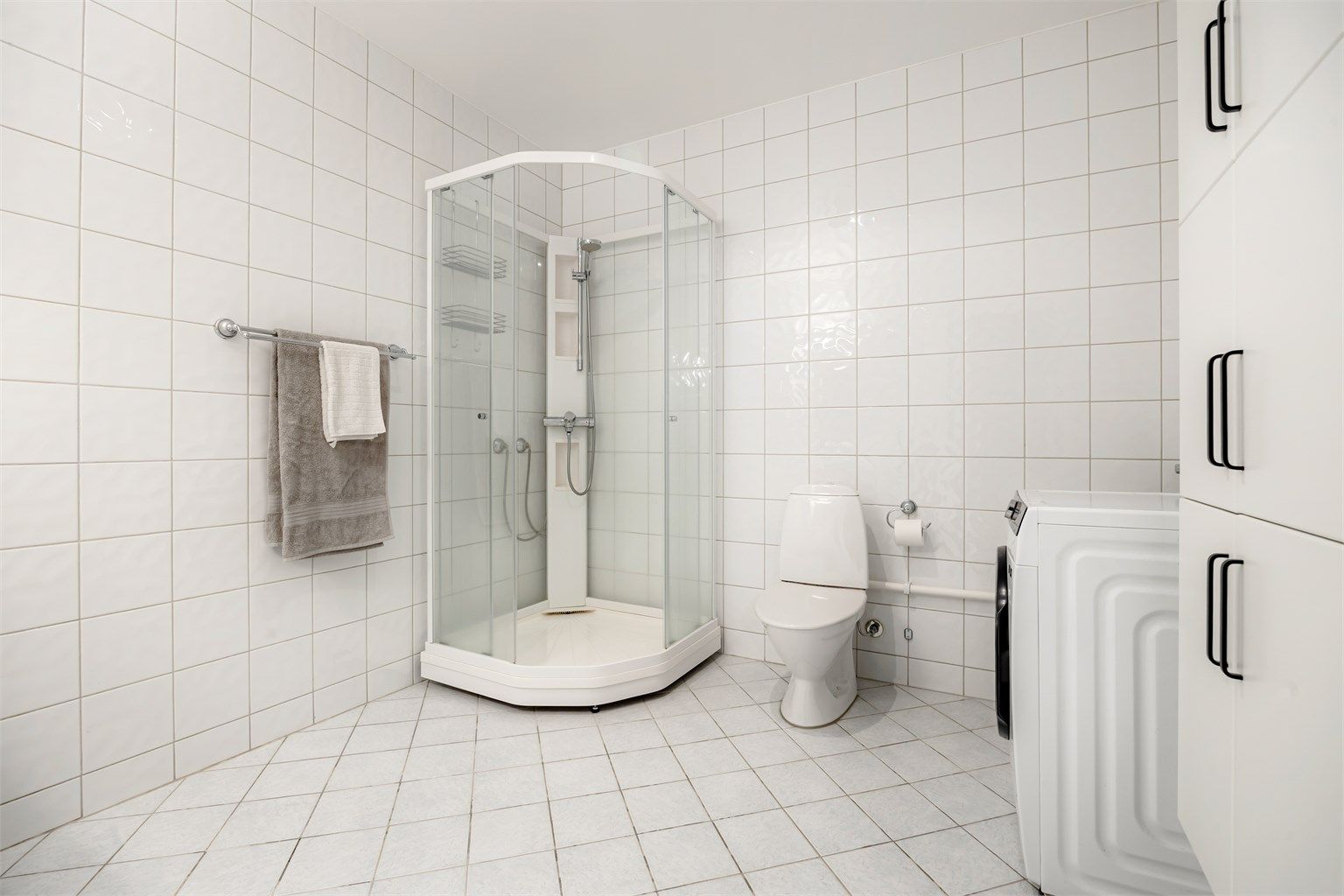 Badet har dusjkabinett, gulvstående toalett og opplegg for vaskemaskin