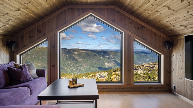 De store vinduene gir et lyst oppholdsrom med åpent utsyn mot fjellet.