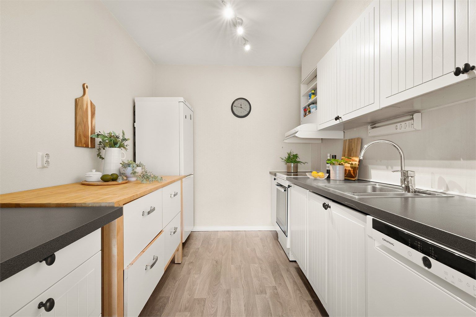 Lys og moderne kjøkkeninnredning med profilerte fronter og benkeplate av laminat.