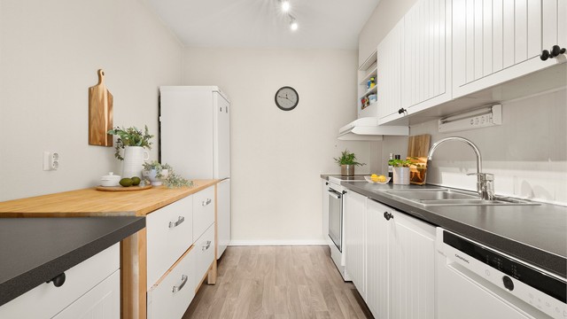 Lys og moderne kjøkkeninnredning med profilerte fronter og benkeplate av laminat.