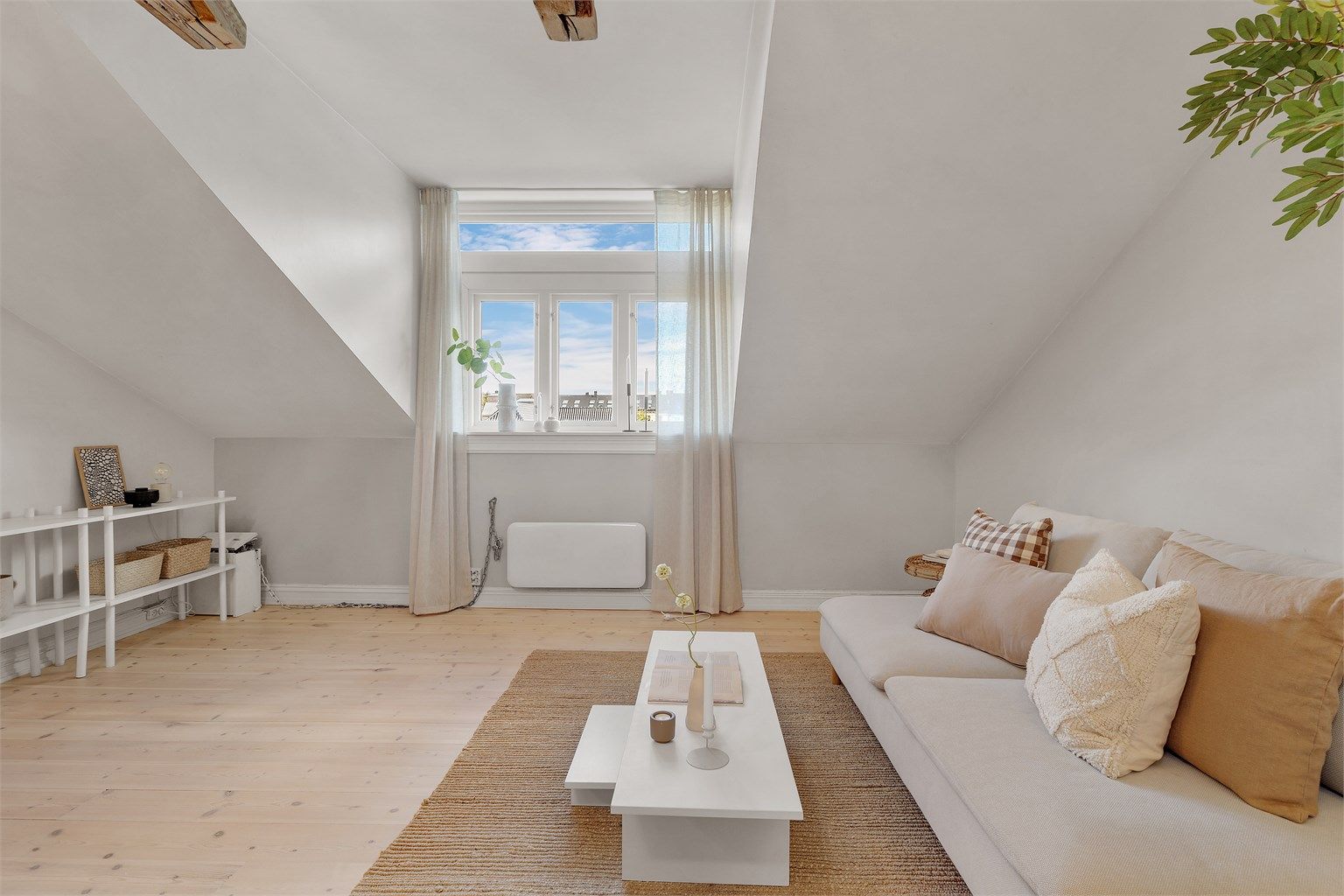 Tiltalende stue i fine fargekombinasjoner med originale bærebjelker og godt lysinnslipp via store vindusflater.