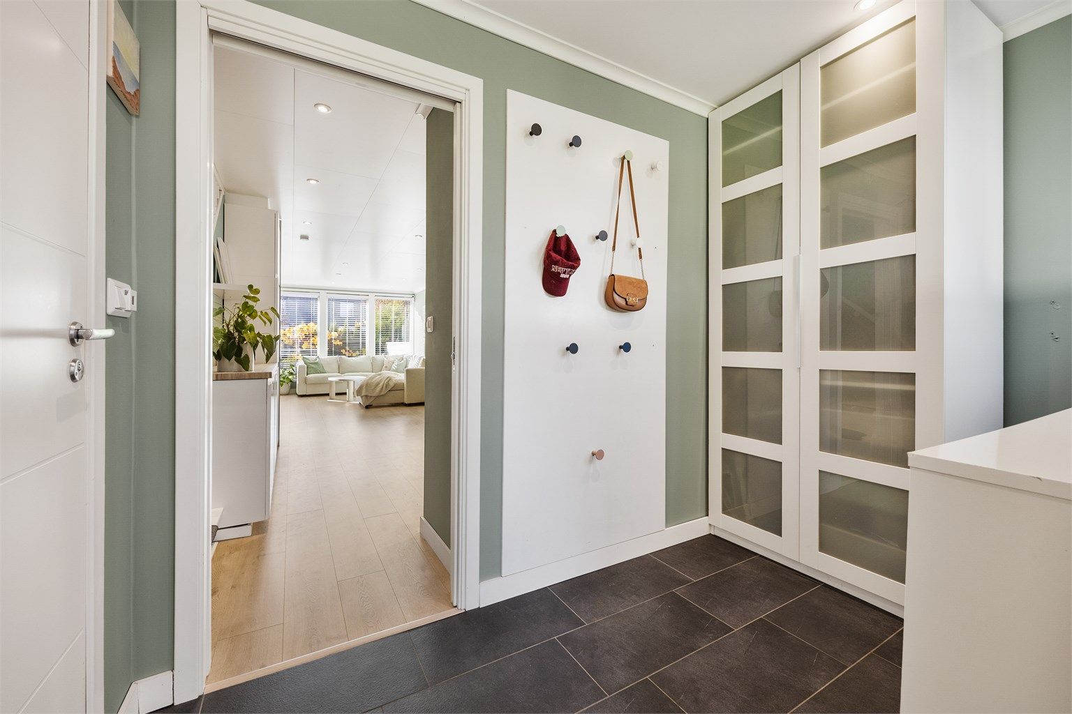 Boligen ønsker deg velkommen inn gjennom en lys, flislagt entré