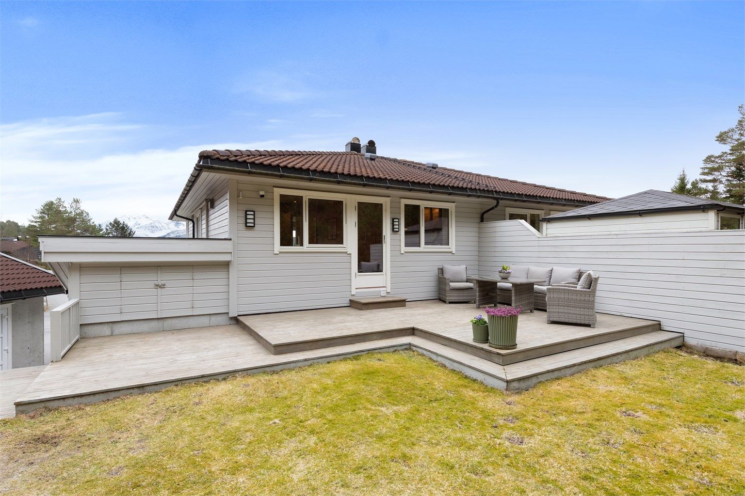 Flott terrasse på 38 m² har utgang fra kjøkkenet og er omkranset av en levegg.