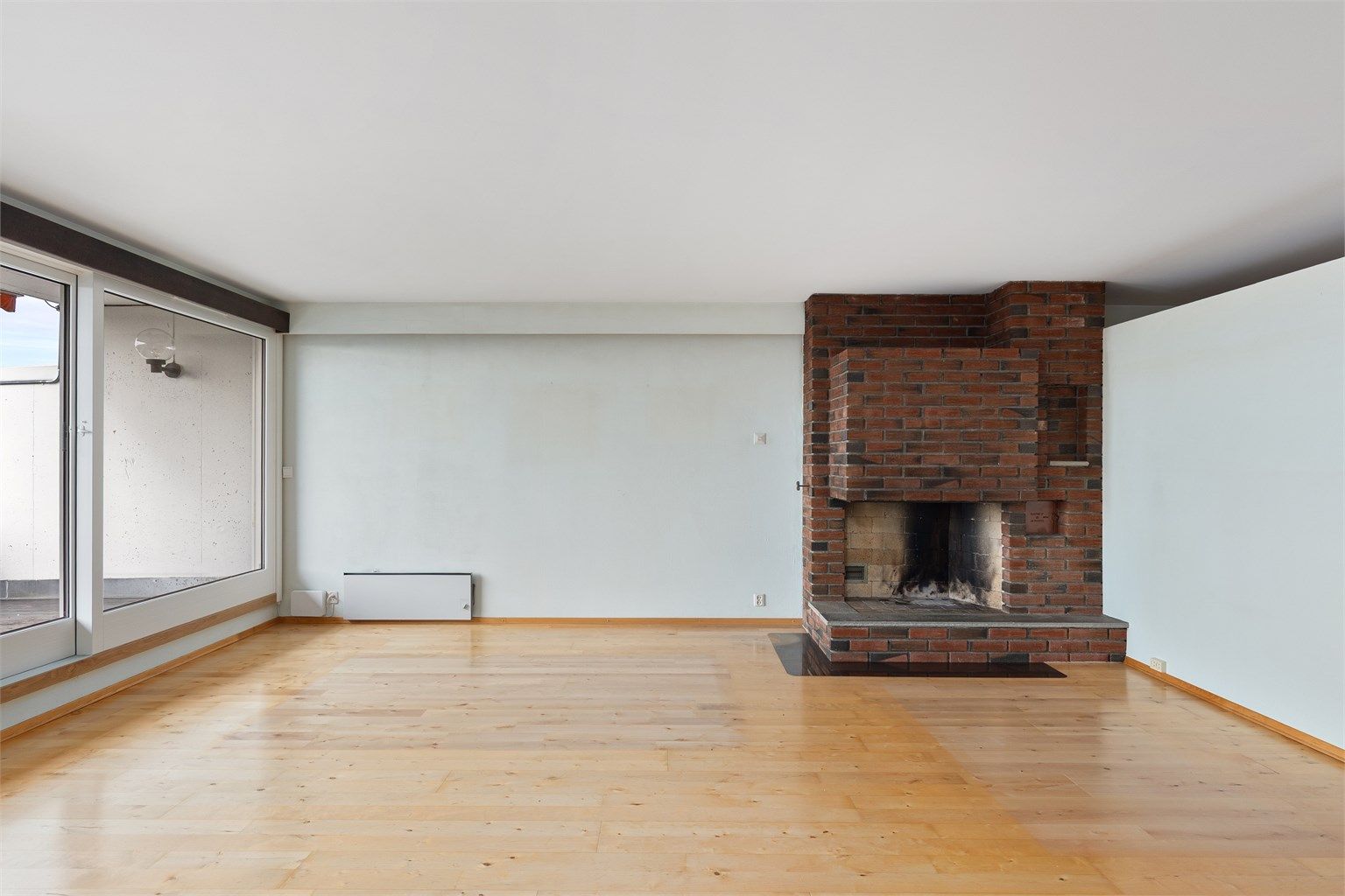 Lys og romslig stue med en sjarmerende åpen teglsteinspeis som kan gi ekstra varme til rommet på kalde vinterdager