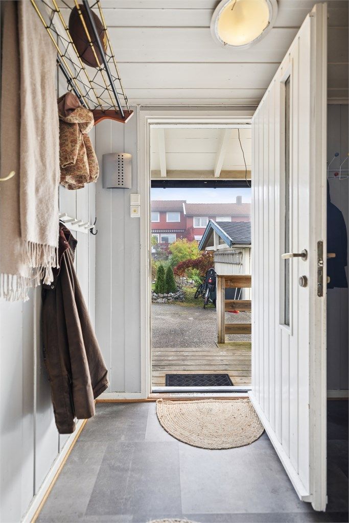 Ved hoveddøra ønskes du velkommen av en overbygget inngang med platting. 