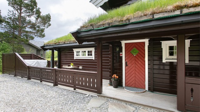 Hytta har en klassisk utforming med torvtak og laftet tømmer.