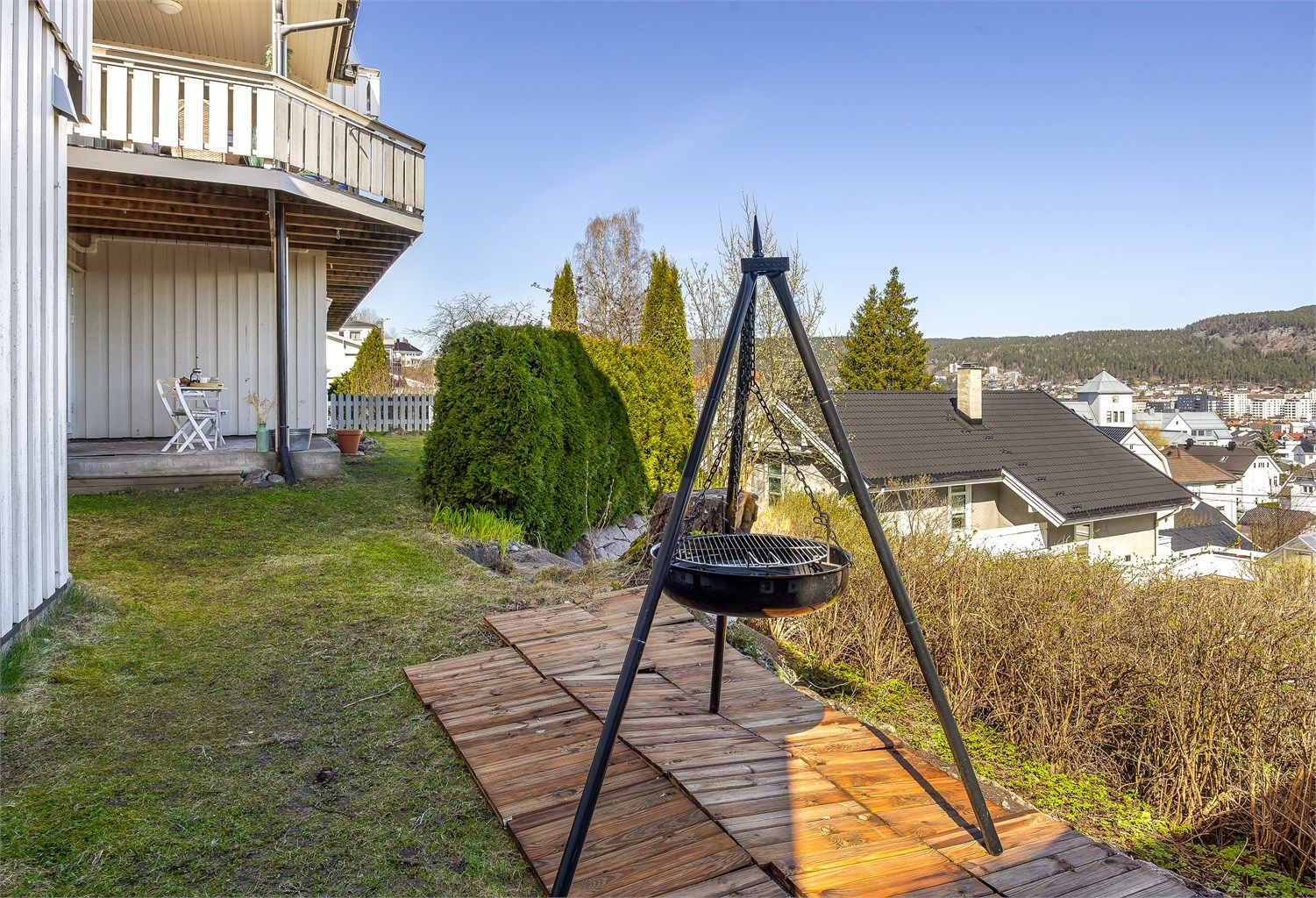 Tomten er opparbeidet med plenarealer og beplantning, og skråner i to nivåer.