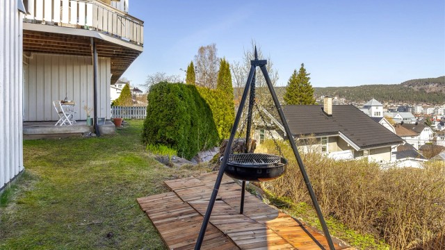 Tomten er opparbeidet med plenarealer og beplantning, og skråner i to nivåer.