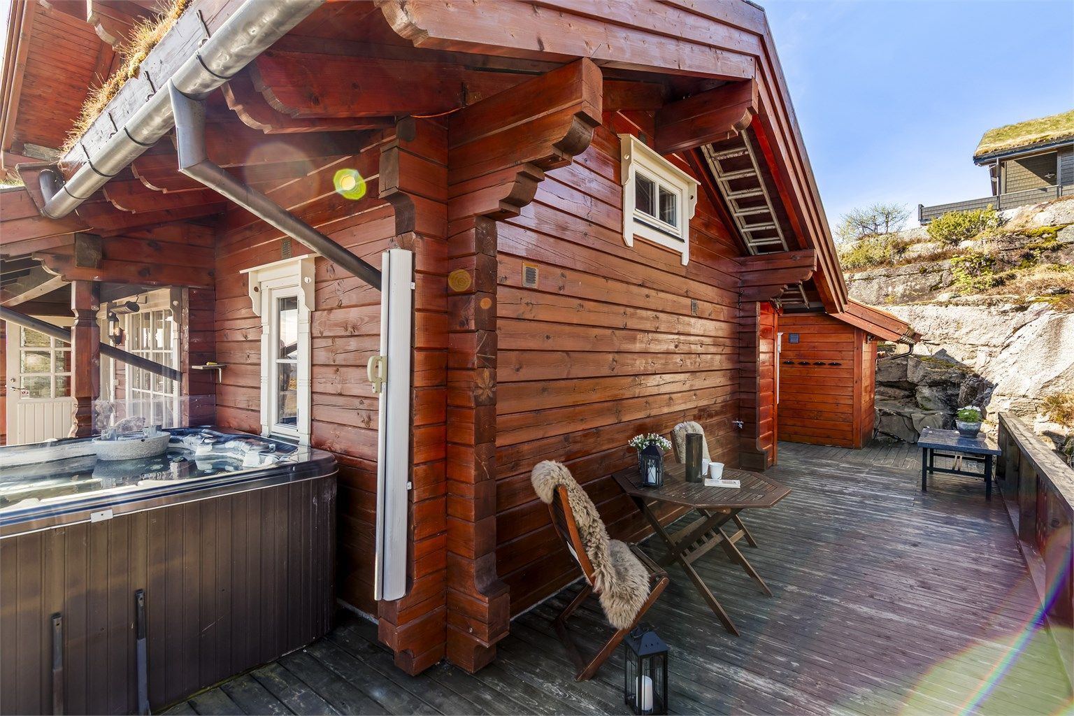 Terrassen er belagt med terrassebord og har rekkverk med stående spiler og glassfelter.