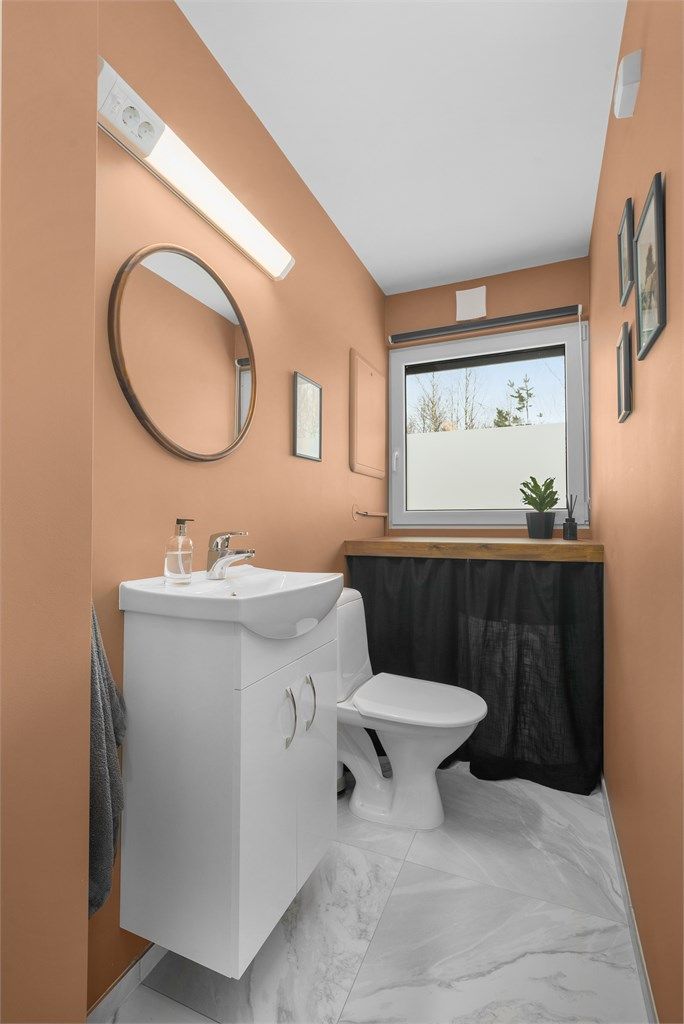 Praktisk separat toalett-rom med flislagte gulv og vegger i malte flater