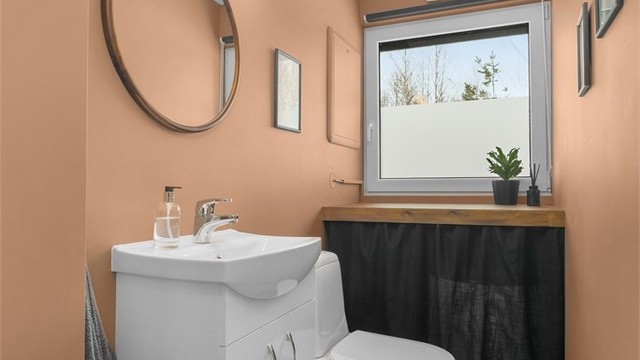 Praktisk separat toalett-rom med flislagte gulv og vegger i malte flater