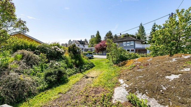 Utsyn fra terrassen mot hagens søndre hjørne som har vært benyttet til biloppstilling. Oppstillingsplass finnes også på gårdsplassen foran inngangspartiet.