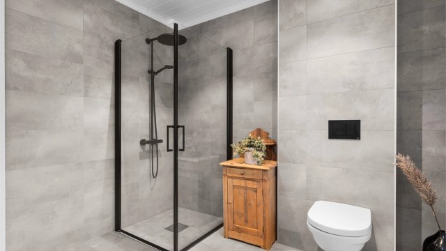 Badet er videre utstyrt med vegghengt toalett og et romslig dusjhjørne med glassdører, dusjarmatur med både hånddusj og regndusj.
