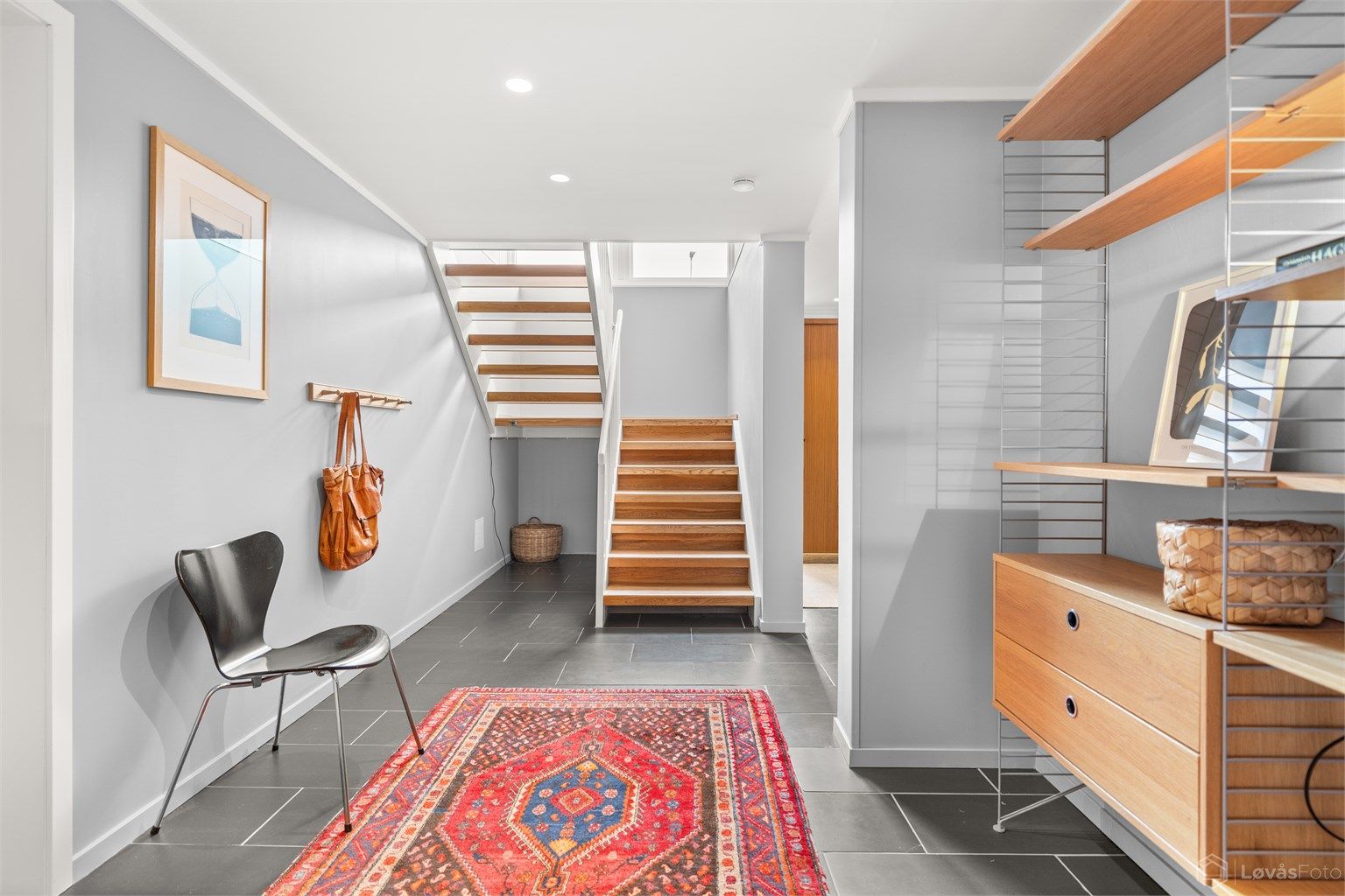 Romslig hall med gulvfliser med varmekabler, downlights i himling og plass til møblering. Entréen har ny påkostet ytterdør fra Bovalls i 2024 med elektronisk kodelås