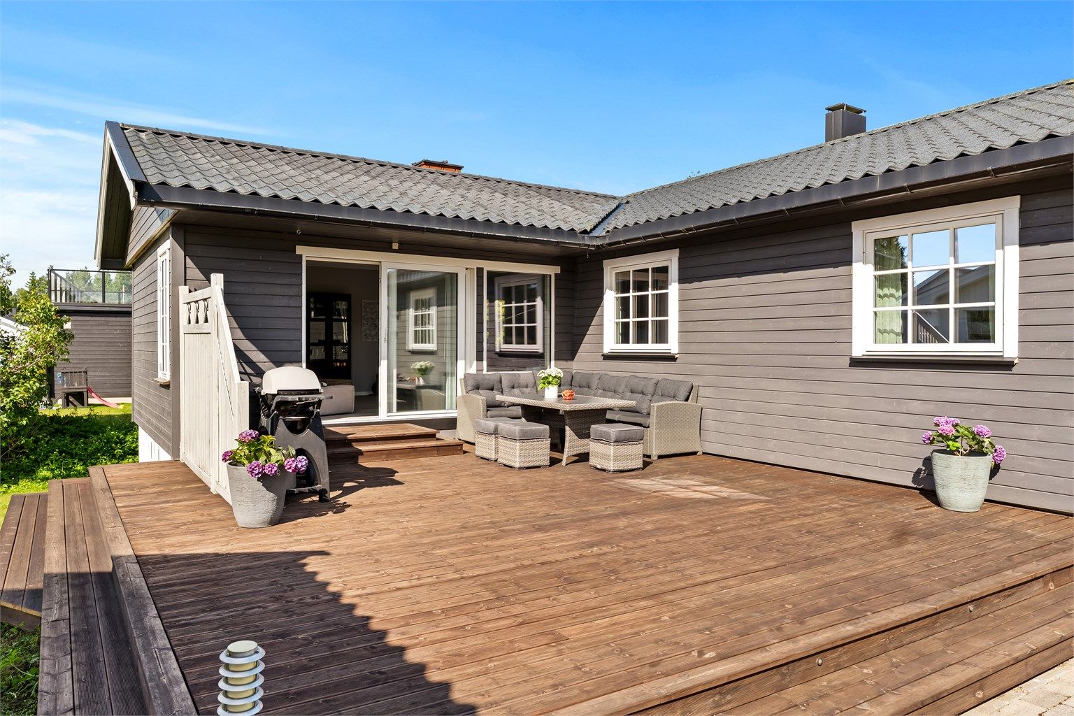 Stor terrasse med direkte utgang fra stuen, på en pent opparbeidet tomt.