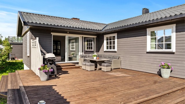 Stor terrasse med direkte utgang fra stuen, på en pent opparbeidet tomt.