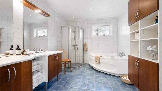 Det romslige badet i underetasjen har både hjørnebadekar og dusjhørne, samt stor og romslig baderomsinnredning