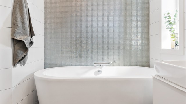 Frittstående badekar med dusjarmatur. Mekanisk avtrekksventil i himling. Glassfliser fra Fired Earth.