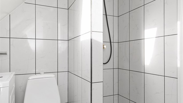 Badet har separat dusjhjørne og toalett plassert under skråtaket.