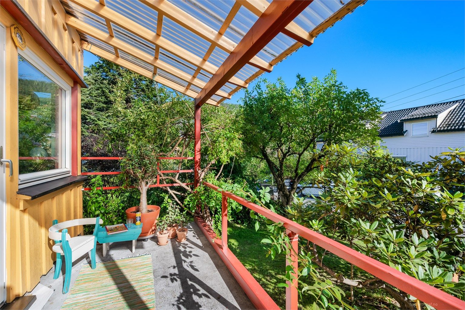 Overbygget østvendt veranda på ca. 6 kvm. Videre er det utvendig trappeadkomst ned til hageområdet. 