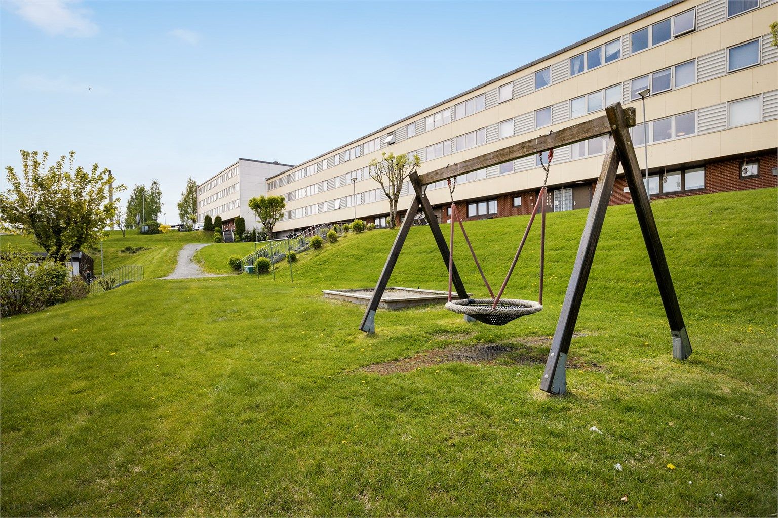  Tomten er fellesareal som er opparbeidet med plen, diverse beplantning, huske og sandkasse tilrettelagt for barnas lek.